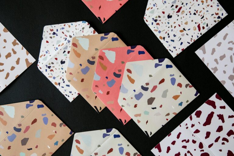Vibrant terrazzo pattern envelopes spread out on a black background, showcasing modern design.